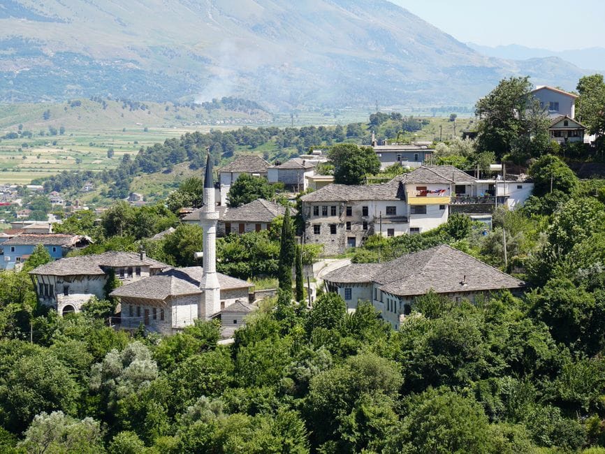 Scenic view of a traditional hilltop village with prominent mosque and lush greenery.