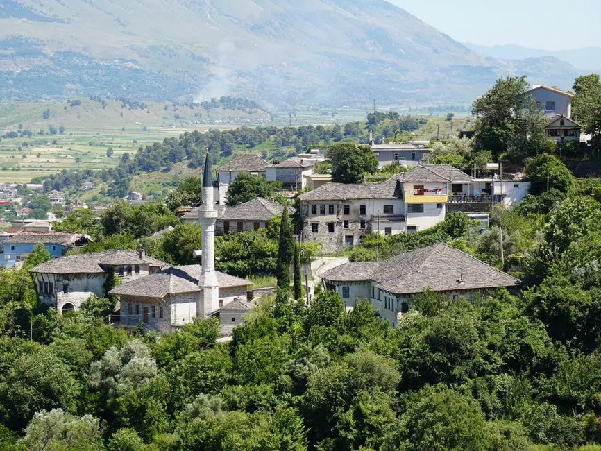 Scenic view of a traditional hilltop village with prominent mosque and lush greenery.