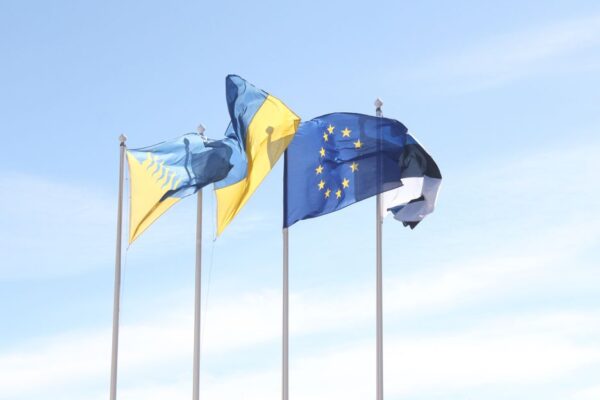 Élargissement UE : ce que ça change vraiment pour les Balkans European Union and Estonian flags wave under a clear blue sky, symbolizing unity and harmony.