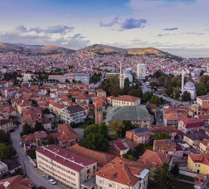 Aerial image showcasing the picturesque townscape of Bitola, North Macedonia, featuring red-roofed buildings and scenic hills.